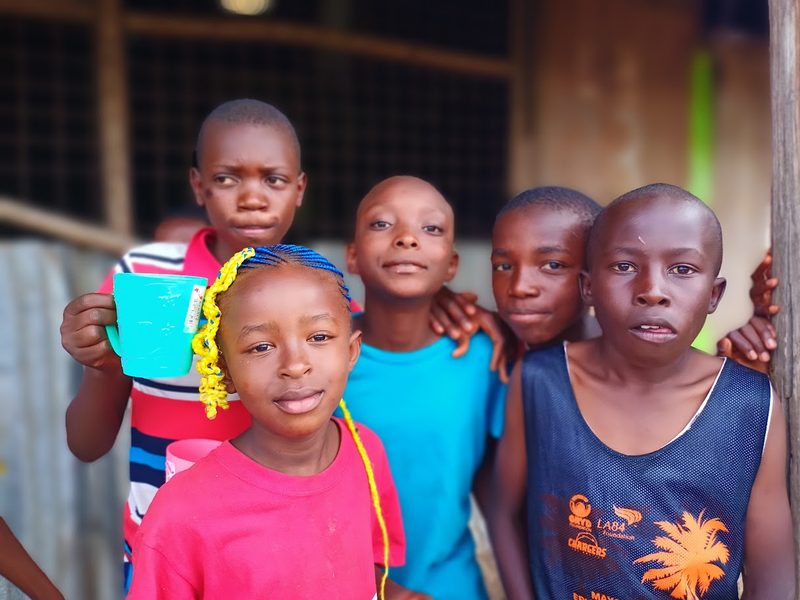 Cinq enfants serrés les uns contre les autres, l’un tient un mug